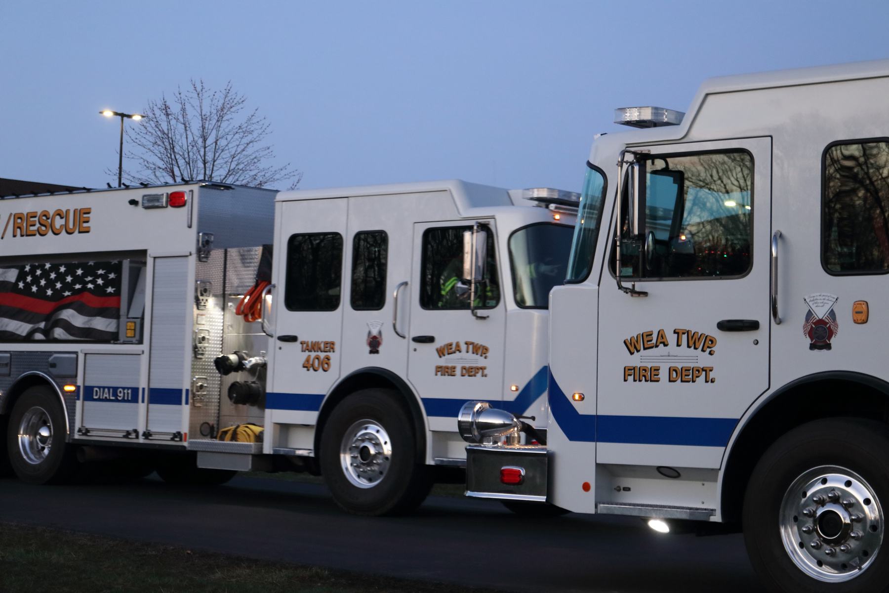 Two white fire trucks parked side by side at dusk