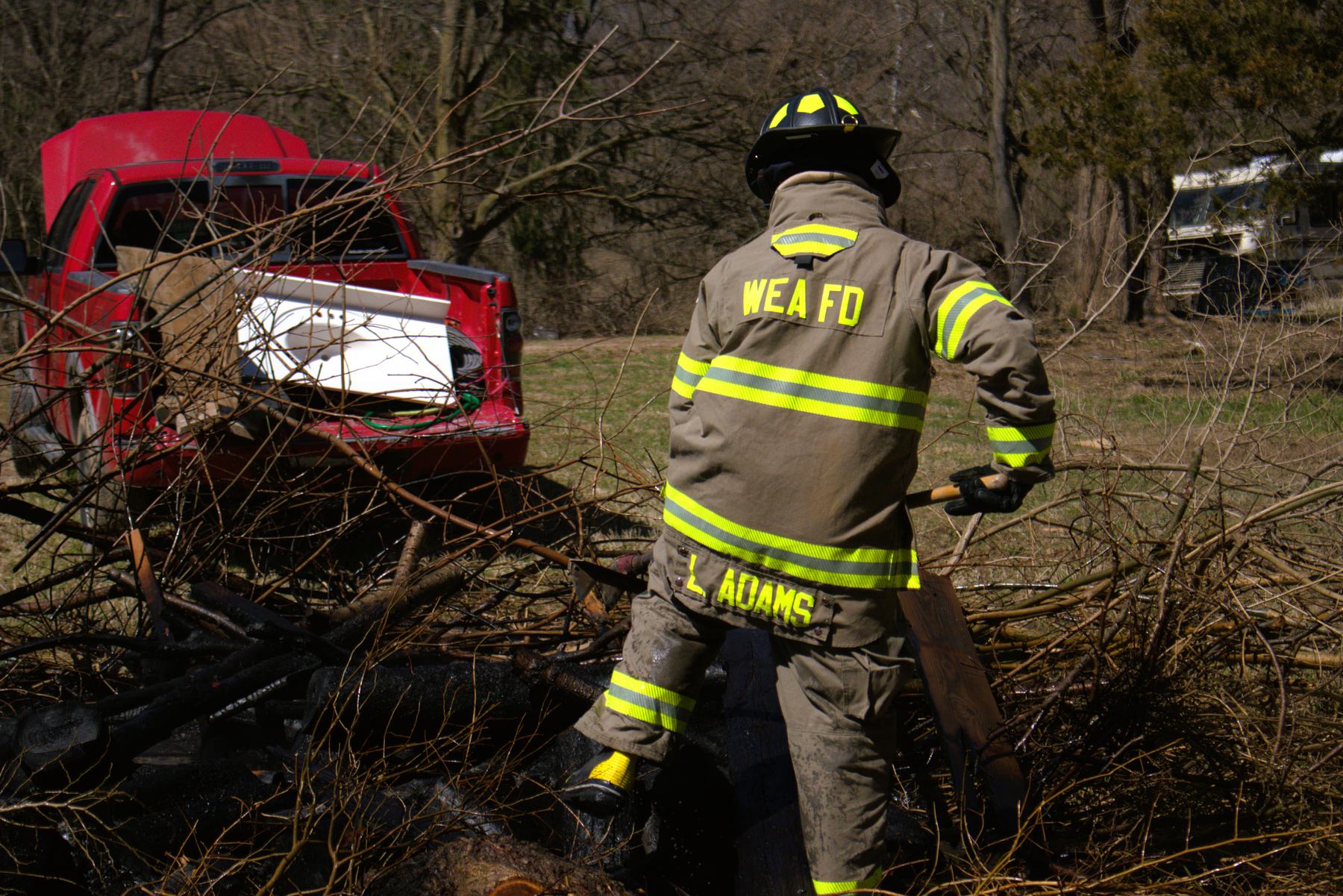 Firefighter pulling apart a smoldering brush pile