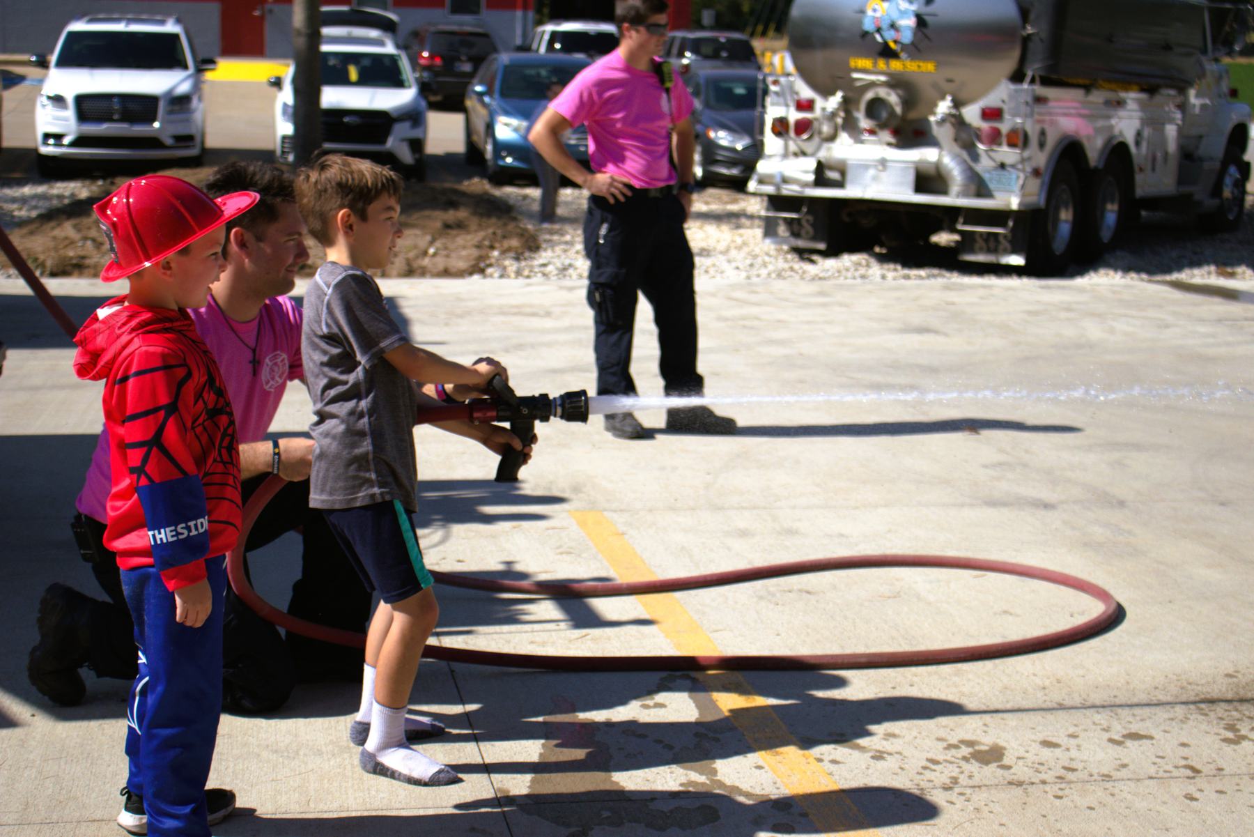 Children taking turns on a fire hose at the open house