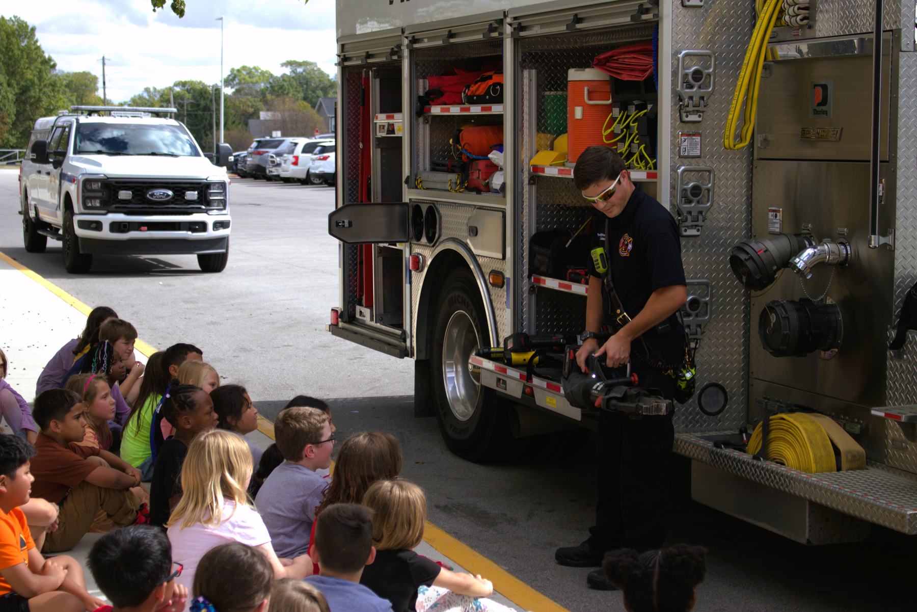 Firefighter showing students tools on the engine