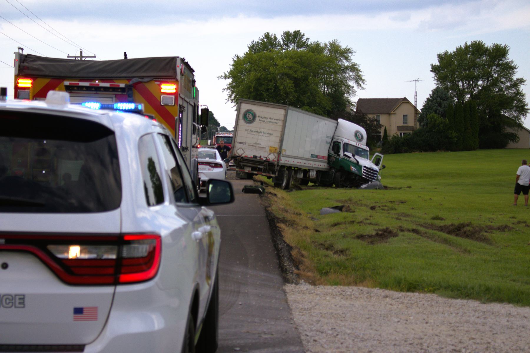 Semi truck off the road beside a police vehicle and fire apparatus